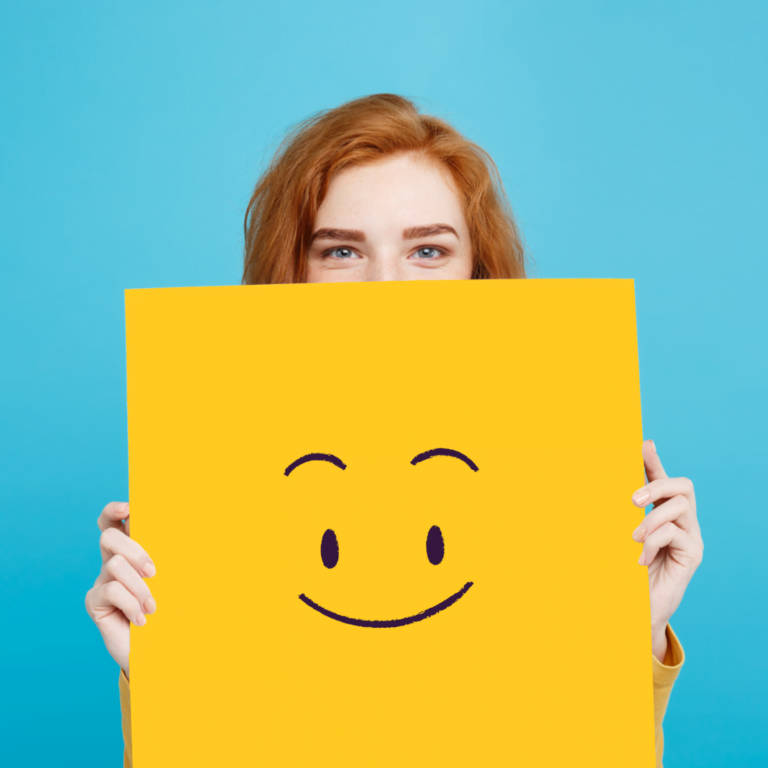 Picture of a redhead woman holding a happy face card for the main GingrTech homepage on business simulation games and experiential learning.